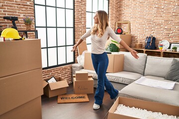 Young blonde woman smiling confident standing with open arms at new home