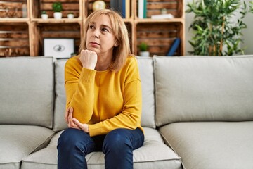 Fototapeta na wymiar Middle age caucasian woman wearing casual clothes sitting on the sofa at home looking stressed and nervous with hands on mouth biting nails. anxiety problem.