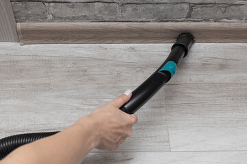 Woman vacuuming the floor with a brush head