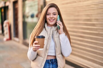 Young blonde woman talking on the smartphone drinking coffee at street