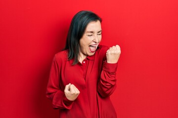 Middle age hispanic woman wearing casual clothes celebrating surprised and amazed for success with arms raised and eyes closed. winner concept.