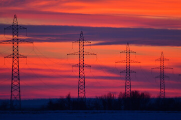 high voltage poles at sunset. red background.