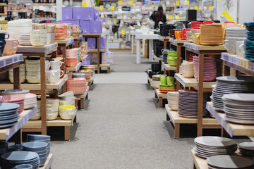 Dishes are sold at the store. Rows of different multicolored cups, bowls and plates for home on...