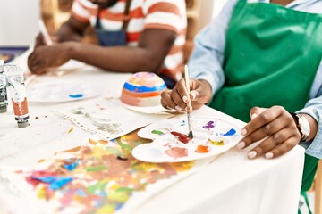 Fototapeta premium Hands of african american painter couple painting pottery sitting on the table at art studio.