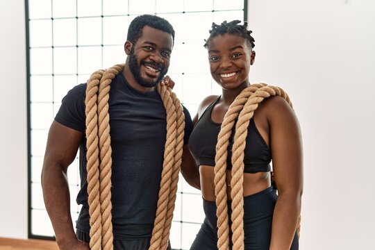 Young african american sporty couple smiling happy holding battle rope at sport center.