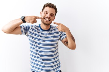 Handsome young man standing over isolated background smiling cheerful showing and pointing with fingers teeth and mouth. dental health concept.