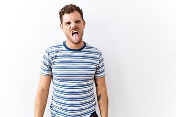 Obraz premium Handsome young man standing over isolated background sticking tongue out happy with funny expression. emotion concept.