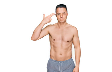 Fototapeta premium Handsome young man wearing swimwear shirtless shooting and killing oneself pointing hand and fingers to head like gun, suicide gesture.