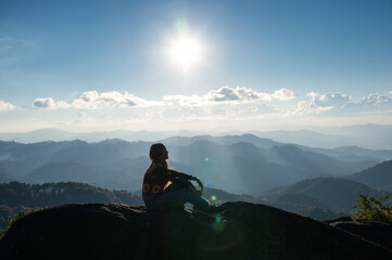 Fototapeta premium Silhouette young hiker woman relaxing and enjoying the sunset view on top of mountain peak at national park