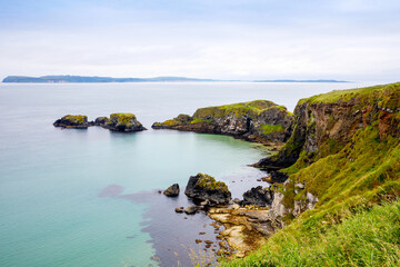 Coast near Carrick-a-Rede Rope Bridge, famous rope bridge near Ballintoy in County Antrim, Northern Ireland on Irish coastline. Wild Atlantic Way on cloudy day.