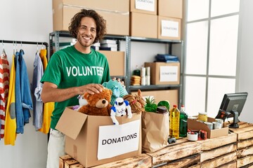 Young hispanic volunteer man smiling happy working at charity center.