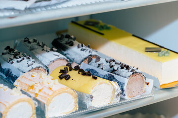 Elongated cakes inside a fridge in a pastry shop.