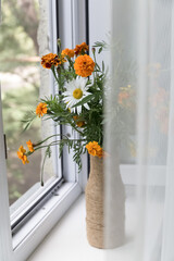 Bouquet of summer flowers in a vase on a white window sill