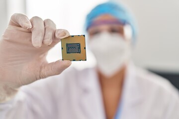 Middle age woman wearing scientist unifor and medical mask holding cpu processor at laboratory
