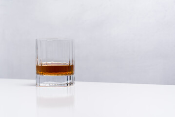 Un vaso de whisky sobre una mesa blanca y fondo claro