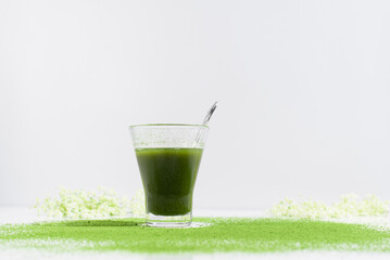 Un vaso de té matcha con polvo de té verde espolvoreado sobre una mesa blanca	