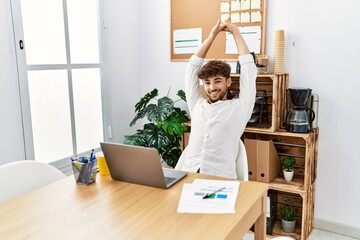 Young arab man relaxed stretching arms working at office