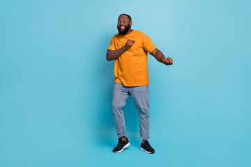Photo of pretty attractive guy dressed orange t-shirt dancing smiling isolated blue color background