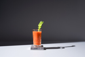 Vaso de jugo de zanahoria con hoja de apio sobre fondo oscuro