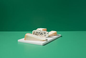Surtido de quesos franceses. Queso de leche de cabra, vaca y oveja sobre un fondo verde	 - obrazy, fototapety, plakaty