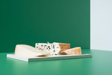 Surtido de quesos franceses. Queso de leche de cabra, vaca y oveja sobre un fondo verde	 - obrazy, fototapety, plakaty