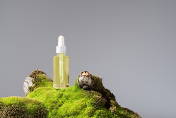 Botella de aceite esencial con cuentagotas sobre un tronco de árbol con musgo. Producto cosmético...