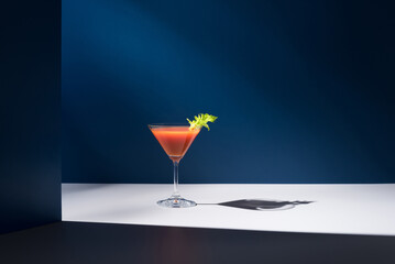 Bloody Mary decorado con hoja de apio en copa de cóctel sobre fondo azul	