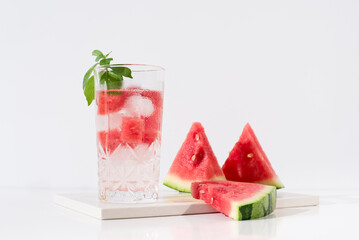 Un vaso de zumo de sandía con trozos de sandia y hielo sobre fondo claro	
