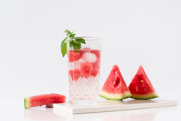 Un vaso de zumo de sandía con trozos de sandia y hielo sobre fondo claro	