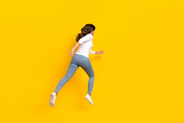 Fototapeta na wymiar Photo of pretty excited lady dressed white shirt running fast jumping high isolated yellow color background