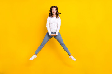 Fototapeta na wymiar Photo of carefree girly lady dressed white shirt jumping high smiling isolated yellow color background