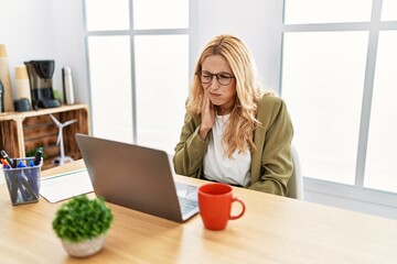 Beautiful blonde woman working at the office with laptop touching mouth with hand with painful expression because of toothache or dental illness on teeth. dentist