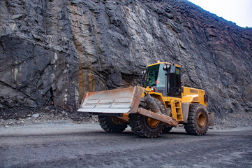 Wheeled bulldozer moves along the roads of an iron ore quarry