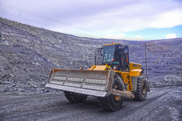Fototapeta premium Wheeled bulldozer moves along the roads of an iron ore quarry