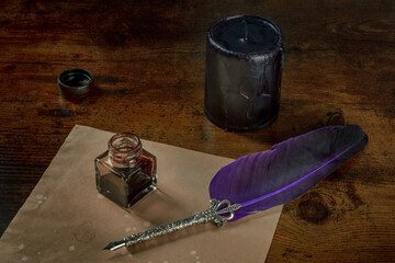 A quill pen with a vintage inkwell, a piece of old paper and a black candle on a dark rustic wooden...