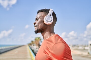 Young african american man smiling confident listening to music at seaside