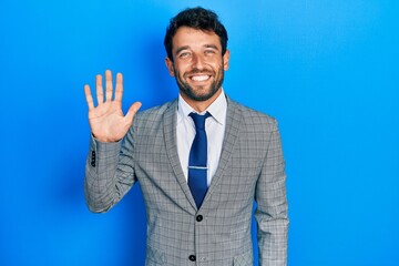 Handsome man with beard wearing business suit and tie showing and pointing up with fingers number five while smiling confident and happy.