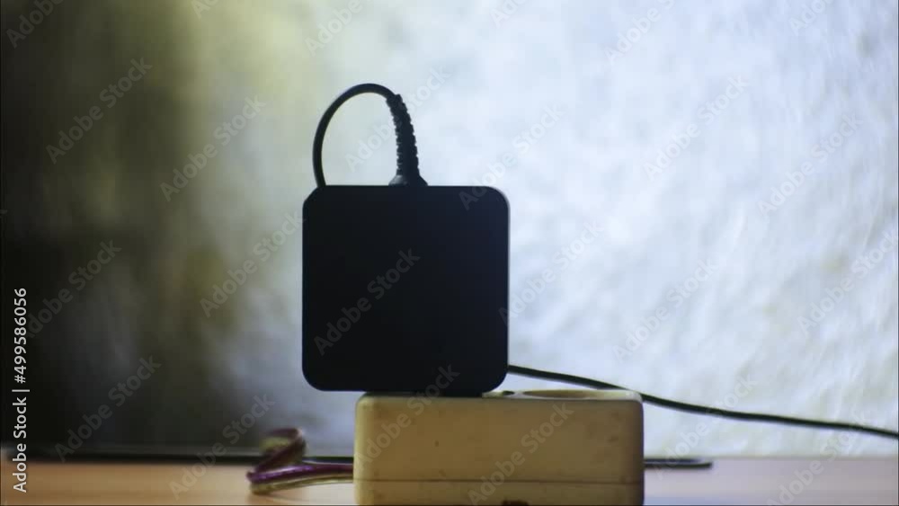 Poster hand plug black notebook charger adapter into power socket close-up view. hand plugs. ready to conne