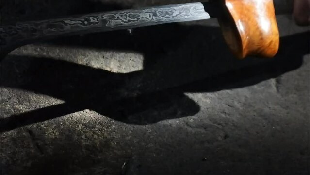 keris craft. A man takes a kris out of its container. Javanese traditional weapon called Keris. Javanese keris in a dark place