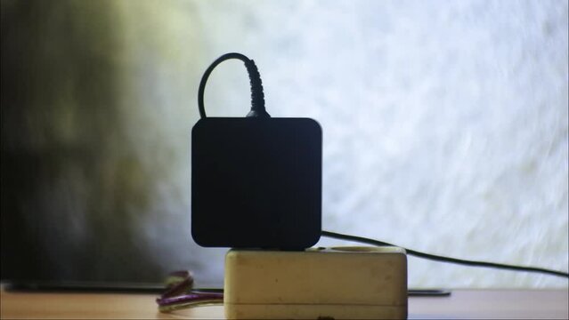 Hand plug black notebook charger adapter into power socket close-up view. Hand plugs. Ready to connect plugging electrical.