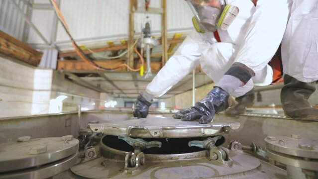 Automatic steam cleaning of the tanker. Worker in chemical protection. A worker makes a chemical cleaning of a tank truck with steam from the inside.