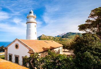 Outside view over the sunlit lighthouse Far del Cap Gros in puerto de soller with the mountain...