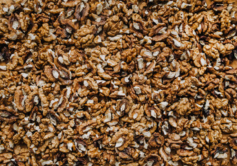Background, texture of many brown pieces of walnuts made of wood, peeled nuts lying on a wooden table. Food photography, top view.
