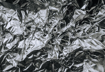 Background, texture of silver shiny foil, colored crumpled paper for packing goods. Close-up photo, top view, copy space, abstraction.