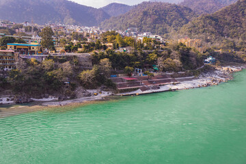 ganges river flowing through mountains with city nestled at riverbank from top angle