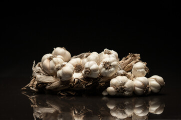 Fragrant Garlic wreath lies on dark background. Agriculture and farming