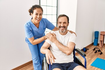 Middle age man and woman smiling confident having physiotherapy session at physiotherapy clinic