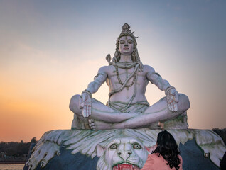 hindu god lord shiva statue in meditation posture with dramatic sky at evening from unique angle
