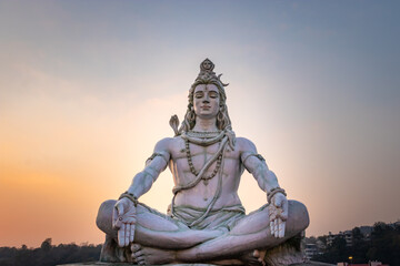 hindu god lord shiva statue in meditation posture with dramatic sky at evening from unique angle