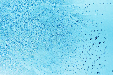 Blue water background with bubbles and drops, flat lay. Abstract clear liquid texture for skincare product backdrop.